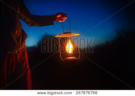 Hand Holds A Large Old Lamp In The Dark. Man Holding The Vintage Lamp With A Candle Outside. Copy Sp