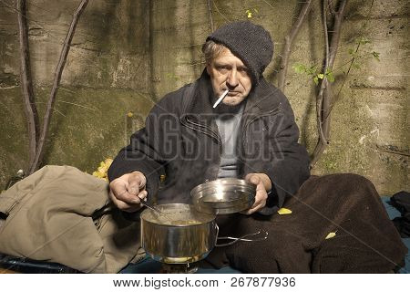 Ugly Pauper Man Living Outdoor Preparing Lentil Soup On Street