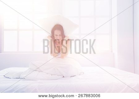 Young Caucasian Woman Covering Her Head And Ears With Pillows.