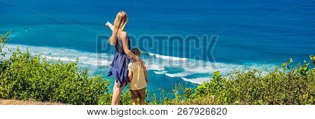 Mom And Son Travelers On A Cliff Above The Beach. Empty Paradise Beach, Blue Sea Waves In Bali Islan