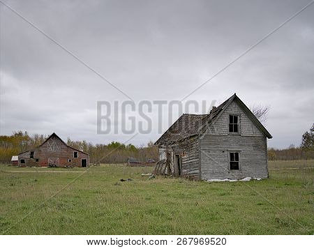 Dreary Abandoned Dilapidated Farm House And Barn With Cloud Skies In Northern Minnesota