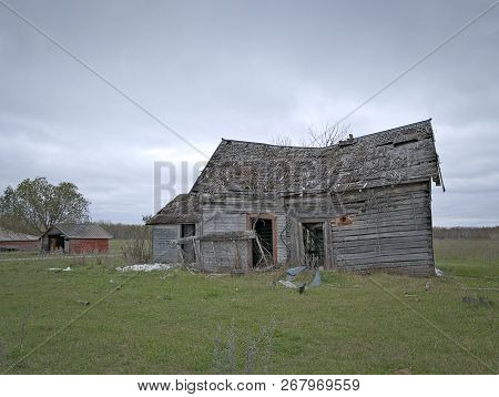 Dreary Abandoned Dilapidated Farm House With Cloud Skies In Northern Minnesota