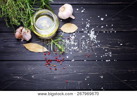 Bottle With Olive Oil With Herb And Spices Ob Black Wooden Background. Top View. Selective Focus. Pl