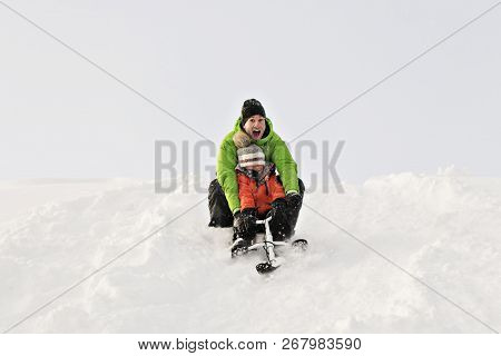 A Nice Father And Son Sitting On Sledge