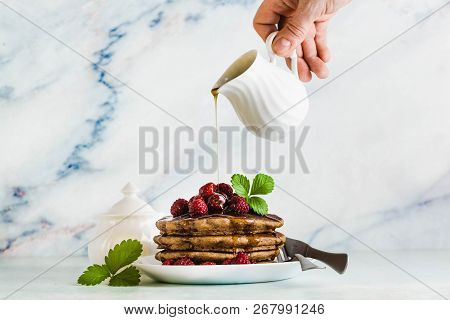Pouring Maple Syrup Over Gluten Free Green Buckwheat Pancakes With Fresh Berries. Delicious Vegan Br