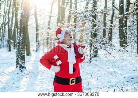 Santa Claus Going With A Bag Of Gifts In The Winter On Snow-covered Field. Santa Claus With Bag Walk