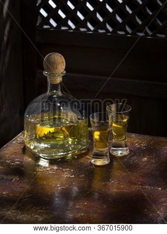 Close Up View Of Bottle Of Tequila Anejo And Glasses On Color Background