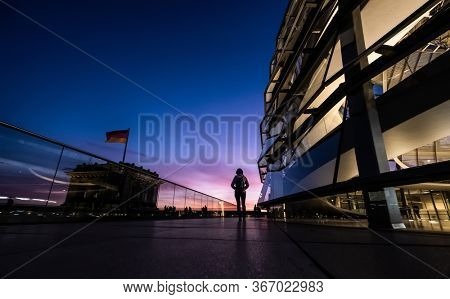 Berlin, Germany - 19 September 2020: Lonely tourist walking along evening Reichstag