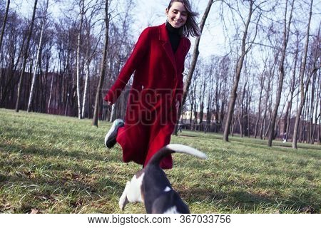 Pretty Young Girl In Redd Coat Playing With Dog Outside In Green Park, Lifestyle People Concept
