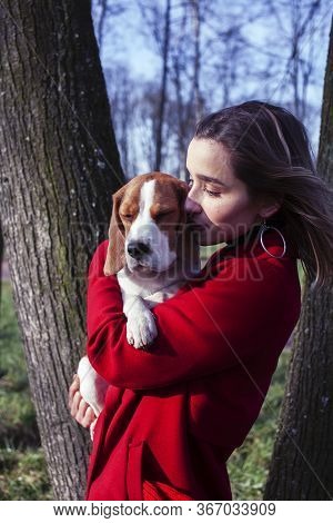 Pretty Young Girl In Redd Coat Playing With Dog Outside In Green Park, Lifestyle People Concept