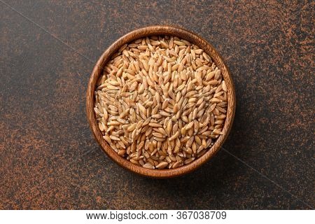 Wholegrain Spelt Farro In Wooden Bowl Isolated On Brown Background. Top View.