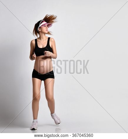 Pregnant Girl With Belly, In Green Sun Visor, Black Sport Shorts And Top, Pink Sneakers. She Is Jogg