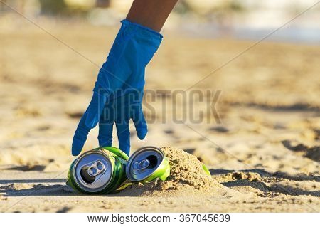 Clean Beach From Trash. Woman Hand Picking Up Empty Soft Drinks Cans Trash From The Beach