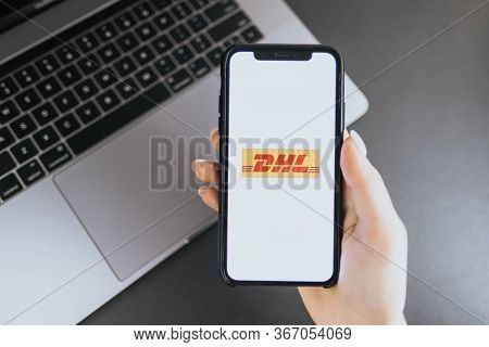 Hand Holding Iphone X With Dhl Logo On The Screen. Dhl Is A Popular Delivery Company.