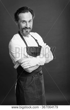 He Is Proficient. Happy Housekeeper Red Background. Mature Housekeeper Wear Gloves And Apron. Profes