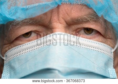 Close Up Portrait Of Sad Senior Adult Dressed In Surgical Face Mask With Ear Straps, Covering Nose F