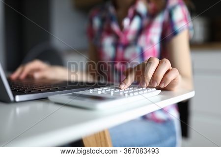 Close-up Of Young Woman Working On Computer And Typing On White Calculator. Female Accounting Family
