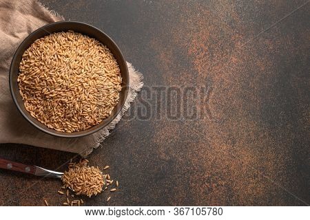 Wholegrain Spelt Farro In Wooden Bowl Isolated On Brown Background. Top View. Space For Text.