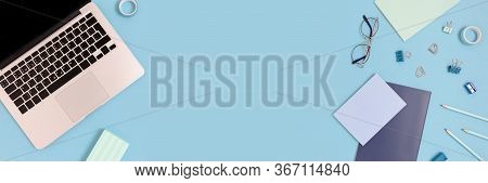 Flaylay Of Laptop And Stationery On A Blue Pastel Background. Workspace Concept Banner With Place Fo