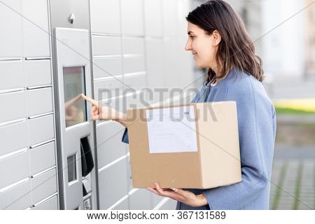 mail delivery and post service concept - happy smiling woman with box at outdoor automated parcel machine choosing operation on touch screen