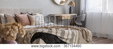 Elegant Round Mirror In Wooden Frame Above Fancy Console Table With Flowers In Vase In Trendy Bedroo