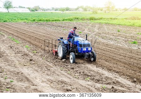 A Farmer On A Tractor Cultivates A Farm Field. Soil Milling, Crumbling And Mixing. Agroindustry, Far