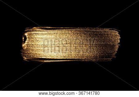 Creative brushstrokes of gold paint isolated on a black background. Gold paint texture.Acrylic gold paint. Smears of cosmetics, blush, highlighter, eye shadow, lipstick.