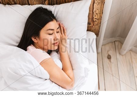 Japanese Woman Sleeping Lying In Comfortable Bed Resting In Bedroom At Home. Wellness And Recreation