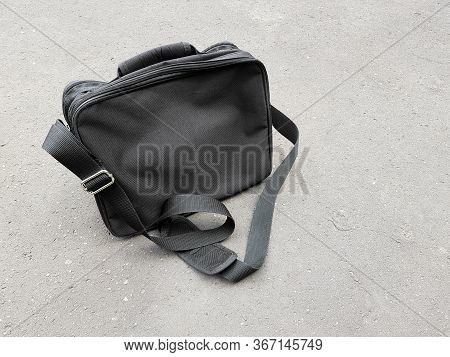 Black Business Satchel Bag Left Behind On The Concrete Floor, Man Fashion Accessories For Carrying A