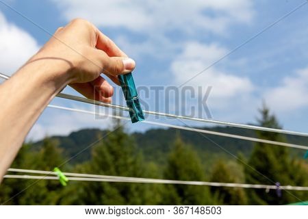 Hand Holding A Clothespin Hanging It On An Empty Wire, Green Eco Forest Natural Outdoor Scenery, Clo