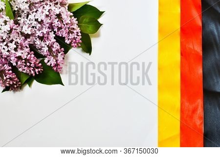 Happy German Unity Day, October 3. German National Flag Made Of Ribbons And A Bouquet Of Lilacs Isol