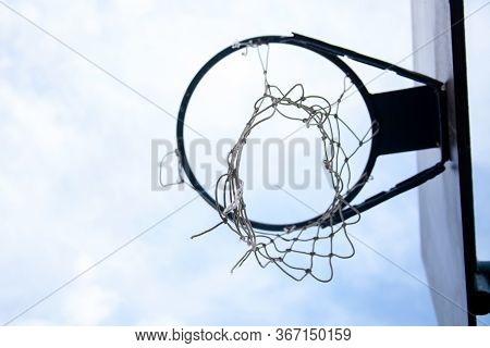 Single Torn Damaged Basketball Hoop Seen From Below, White Sky, Closeup. Sub Urban Playground Area, 