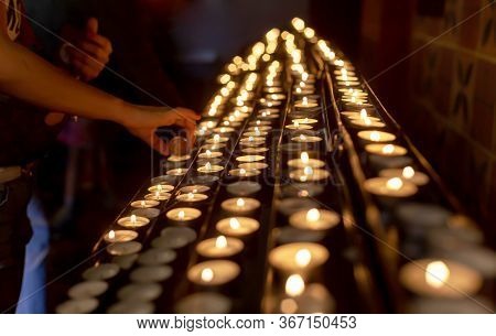Lots Of Votive Candles Lit, A Hand Lighting A New Candle. Memory And Prayer Simple Spiritual Religio