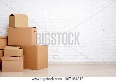 Moving Day Concept - Cardboard Boxes And Copy Space Over White Brick Wall Background