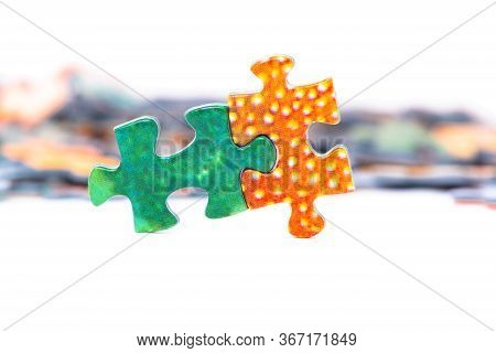 Two Bright Puzzle Pieces Connected In Front Of Separated Pieces. White Background.