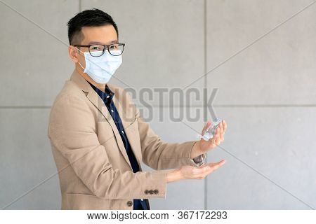 Business Man Wearing Mask And Using Personal Sanitizer To Cleaning His Hand In Office To Keep Hygien
