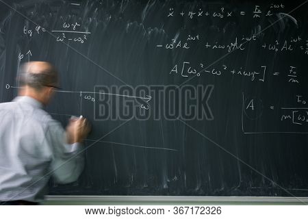 Math teacher drawing   fuction graph on a blackboard during mathclass (motion blurred image)