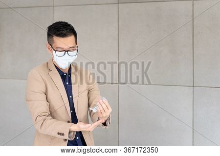 Business Man Wearing Mask And Using Personal Sanitizer To Cleaning His Hand In Office To Keep Hygien