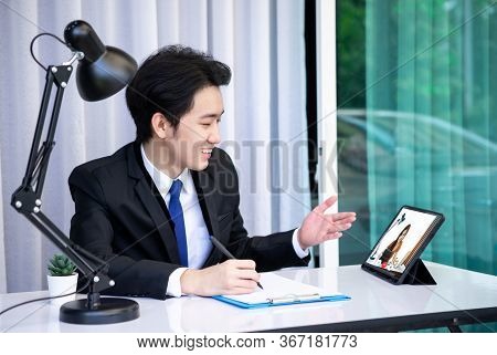 Asian Business Man Dringking Coffee Wearing Suit, Enjoying Watching Educational Webinar On Laptop Or
