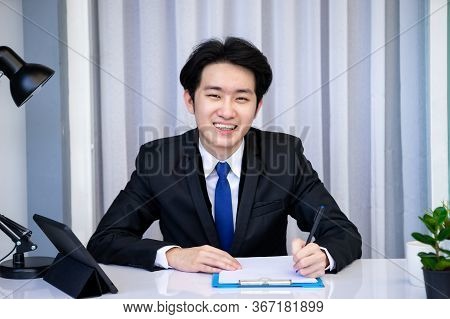 Asian Business Man Dringking Coffee Wearing Suit, Enjoying Watching Educational Webinar On Laptop Or