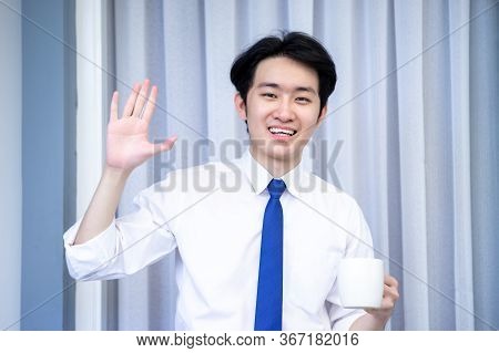 Asian Business Man Dringking Coffee Wearing Suit, Enjoying Watching Educational Webinar On Laptop Or