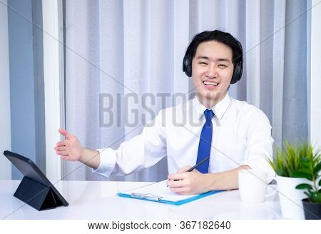 Asian Business Man Dringking Coffee Wearing Suit, Enjoying Watching Educational Webinar On Laptop Or