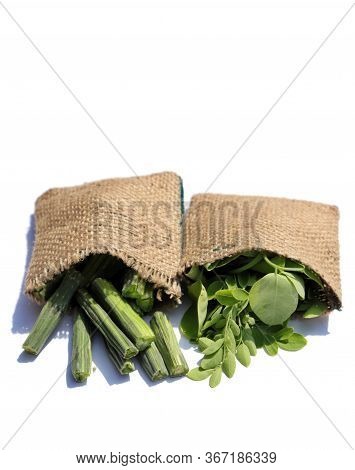 Moringa Oleifera Leaves And Drumstick Pods In Jute Sacks Isolated In White Background In Vertical Or
