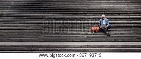 Young Businessman With Laptop Sitting On Stairs Ramp