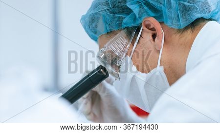 Close Up. Serious Scientist Looking Through A Laboratory Microscope.