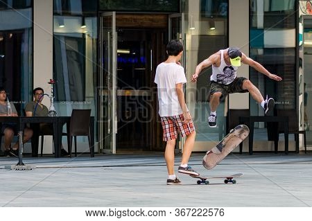 Skaters Doing Tricks With Skateboards In Modern Sanlitun Area Of Beijing, China