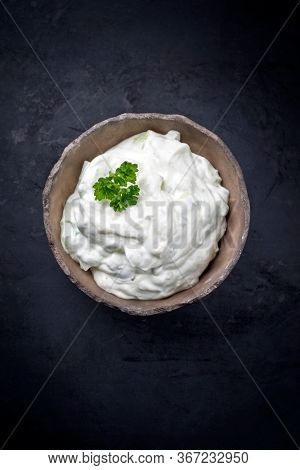 Traditional Greek tzatziki fat yogurt offered with parsley as top view in a rustic modern design bowl with copy space 
