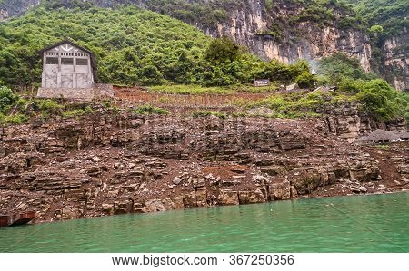 Wushan, Chongqing, China - May 7, 2010: Mini Three Gorges. Gray Cement Barn Built Above Brown Stone 
