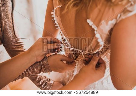 Mom Helps The Bride To Wear A Wedding Dress