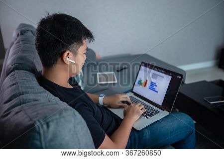 Asian Businessman Using Wireless Earphones And Using Computer Notebook Working From Home.he Is Prepa